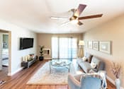 Thumbnail 2 of 9 - A living room with a ceiling fan and a couch.