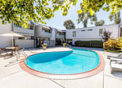 Thumbnail 7 of 9 - A swimming pool in a backyard with a white fence and a house in the background.