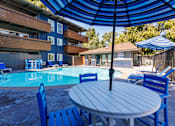 Thumbnail 6 of 9 - A blue and white pool area with a table and chairs.