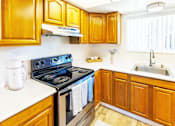 Thumbnail 2 of 9 - A kitchen with wooden cabinets and a black stove top oven.