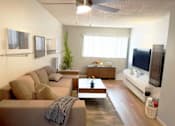 Thumbnail 2 of 8 - A living room with a brown couch and a television.