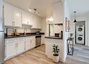 Thumbnail 2 of 11 - A modern kitchen with white cabinets and a wooden floor.