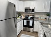 Thumbnail 4 of 12 - A kitchen with a refrigerator, microwave, oven, and sink.