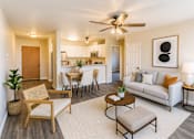 Thumbnail 1 of 12 - A living room with a white couch, a wooden chair, and a ceiling fan.
