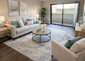 Thumbnail 2 of 12 - A living room with a grey couch, a coffee table, and a plant.
