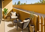 Thumbnail 8 of 12 - A patio with a table, chairs, and a potted plant.