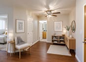 Thumbnail 3 of 12 - A living room with a chair, a table, and a ceiling fan.