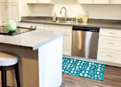 Thumbnail 3 of 9 - A kitchen with a stove, sink, and bar stool.