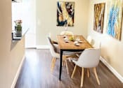 Thumbnail 2 of 9 - A dining room with a table set for two and a ceiling fan.