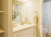 Thumbnail 6 of 14 - A bathroom with a white sink and a mirror above it.