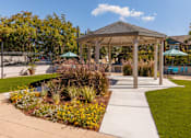 Thumbnail 2 of 9 - A gazebo is surrounded by a garden with a pond and a fence.