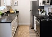 Thumbnail 2 of 14 - A kitchen with black countertops and white cabinets.