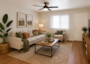 Thumbnail 1 of 7 - A living room with a white couch, a coffee table, and a ceiling fan.