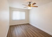 Thumbnail 6 of 19 - A room with a ceiling fan and wooden flooring.