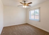 Thumbnail 8 of 19 - A room with a ceiling fan and carpeted floor.