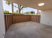Thumbnail 12 of 19 - A patio with a white wall and a brown fence.