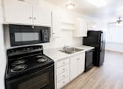 Thumbnail 4 of 19 - A black stove and microwave in a white kitchen.