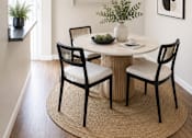 Thumbnail 3 of 9 - A dining room with a round table and chairs.