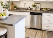 Thumbnail 2 of 9 - A kitchen with a white counter and a stainless steel dishwasher.