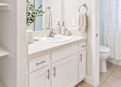 Thumbnail 3 of 13 - A white bathroom with a sink, mirror, and toilet.