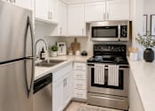 Thumbnail 5 of 13 - A modern kitchen with a refrigerator, microwave, and oven.