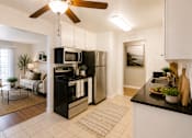 Thumbnail 2 of 12 - A modern kitchen with black countertops and stainless steel appliances.