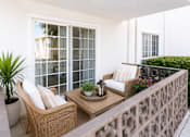 Thumbnail 7 of 12 - A patio with a wicker chair and table.