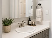 Thumbnail 6 of 14 - A bathroom with a white sink and a mirror above it.
