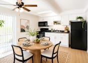 Thumbnail 2 of 9 - A black refrigerator is in a kitchen with a table and chairs.