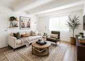 Thumbnail 1 of 9 - A living room with a white couch, a green armchair, and a coffee table.