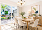 Thumbnail 7 of 14 - A dining room with a table and chairs and a balcony with plants.