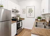 Thumbnail 5 of 10 - A modern kitchen with a stainless steel refrigerator and a sink.