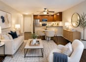 Thumbnail 1 of 9 - A modern living room with a white sofa, a coffee table, and a ceiling fan.
