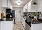 Thumbnail 2 of 11 - A kitchen with black countertops and white cabinets.