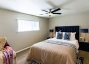 Thumbnail 3 of 6 - A bedroom with a bed, a chair, and a ceiling fan.