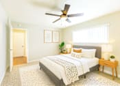 Thumbnail 3 of 7 - A bedroom with a bed, a ceiling fan, and a nightstand with a plant on it.