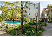Thumbnail 7 of 9 - an apartment building with a swimming pool and palm trees