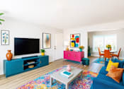 Thumbnail 1 of 8 - A living room with a blue couch and a television on a cabinet.