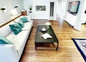 Thumbnail 4 of 10 - A living room with a white couch and a black coffee table.