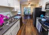 Thumbnail 4 of 8 - A kitchen with a black fridge and wooden floors.