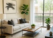 Thumbnail 1 of 8 - A living room with a white couch, a coffee table, and a ceiling fan.