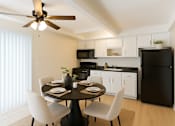 Thumbnail 2 of 10 - A black refrigerator sits in a kitchen with white cabinets and a table set for two.