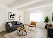 Thumbnail 1 of 10 - A living room with a grey couch, a coffee table, and a chair.