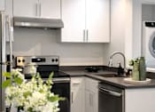 Thumbnail 3 of 14 - A modern kitchen with a stainless steel refrigerator and a black oven.