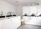 Thumbnail 13 of 14 - A laundry room with a washer and dryer on the left and a stack of dryers on the right.
