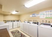 Thumbnail 8 of 11 - A laundromat with washers and dryers lined up.