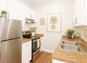 Thumbnail 2 of 10 - A kitchen with a stainless steel refrigerator and white cabinets.