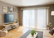 Thumbnail 2 of 9 - A living room with a television, a couch, and a plant.