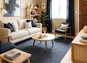 Thumbnail 1 of 5 - A living room with a white sofa, a wooden coffee table, a blue chair, and a large abstract painting on the wall.