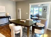Thumbnail 3 of 10 - A dining room with a dark wooden table and white chairs.